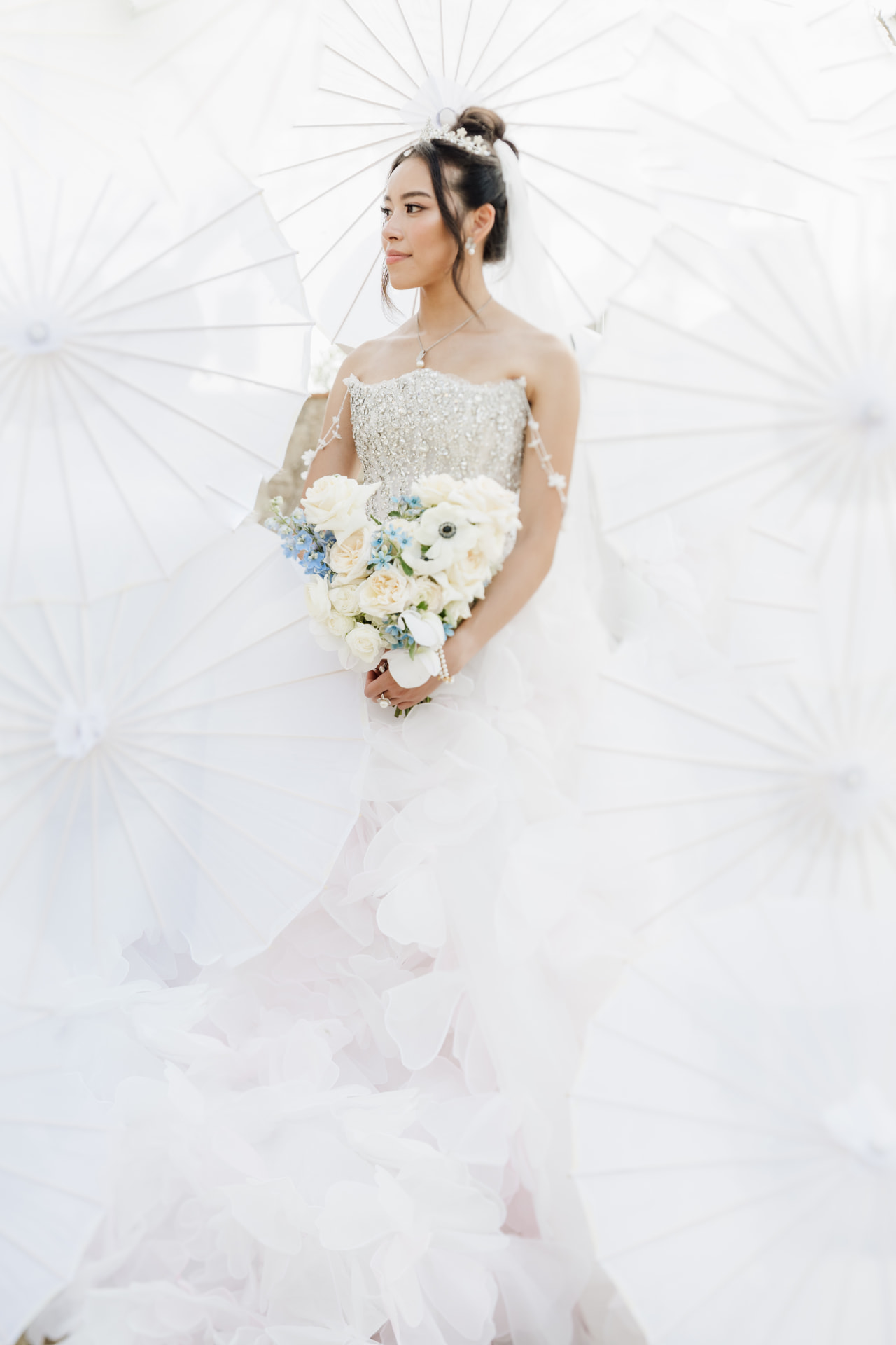 Bride with a bouquet standing among white paper parasols