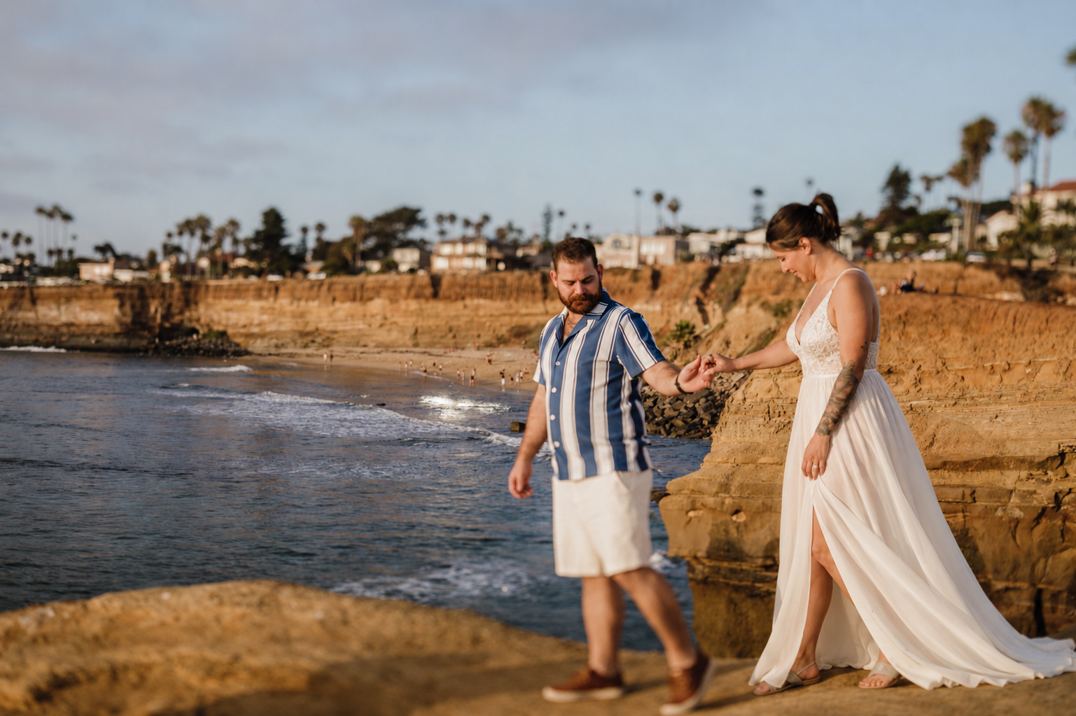 Couple walking hand in hand along the San Diego sunset cliffs at golden hour