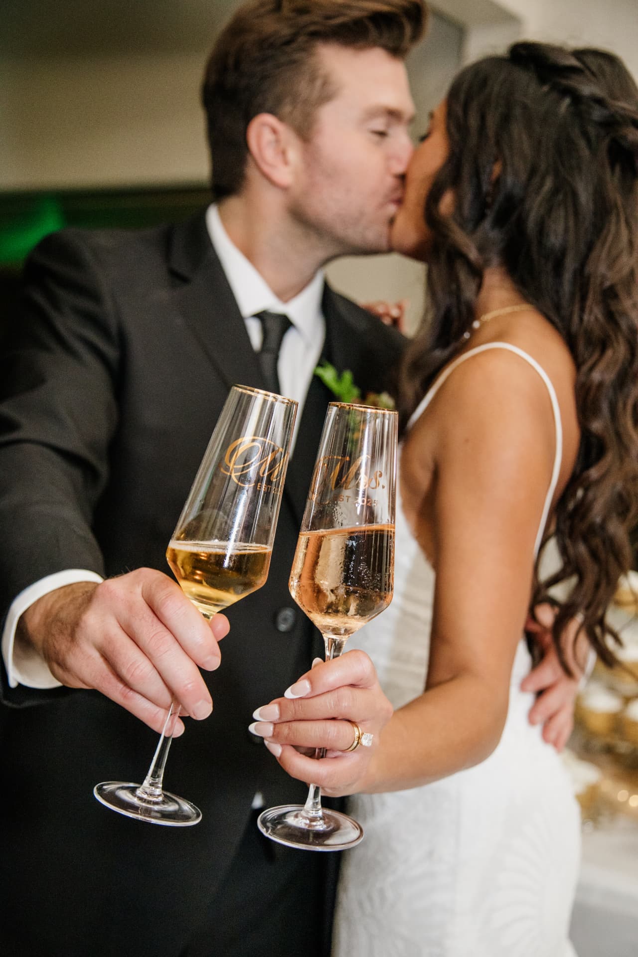 Bride and groom kissing while toasting engraved champagne flutes