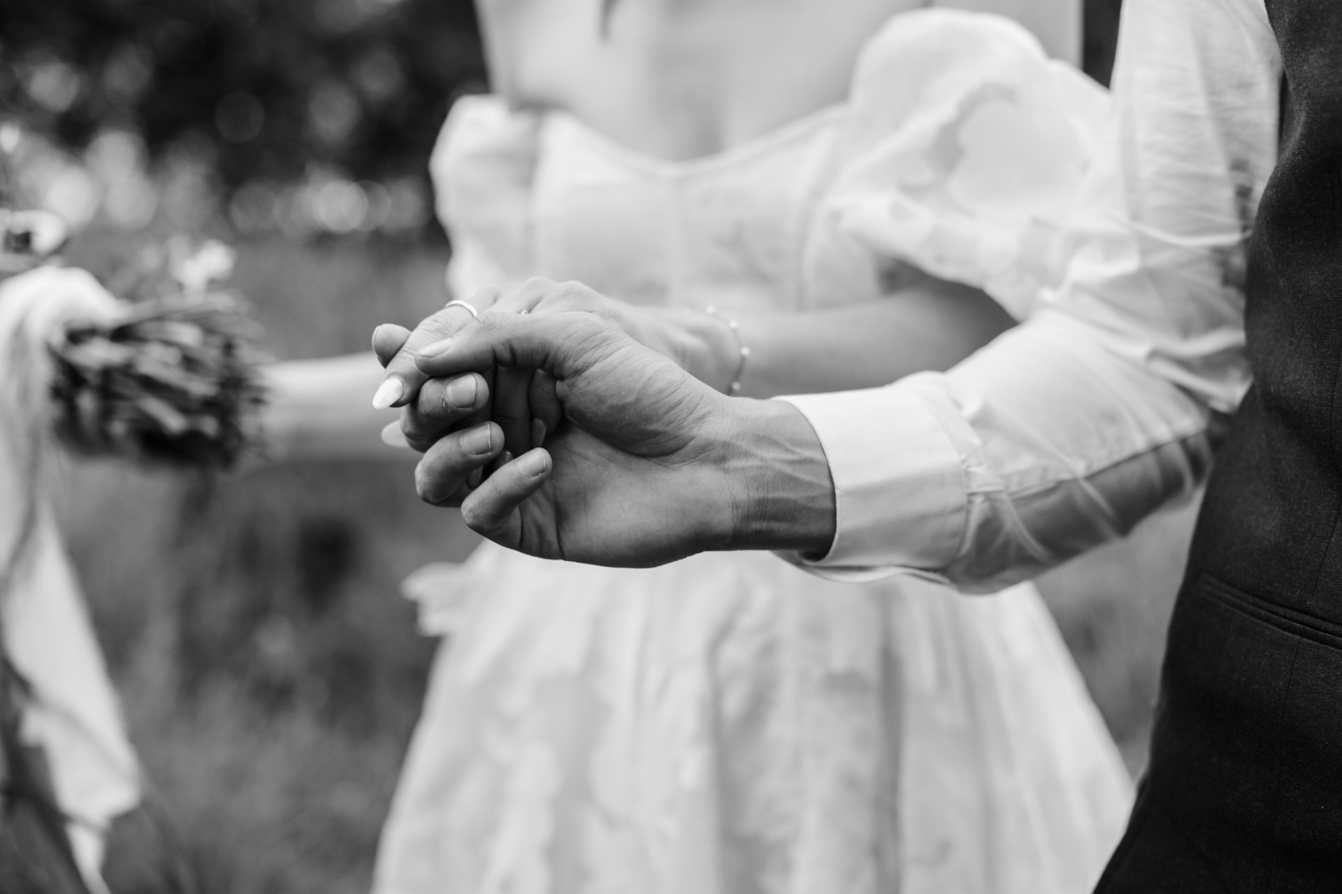 Bride and groom holding hands during their wedding ceremony in black and white