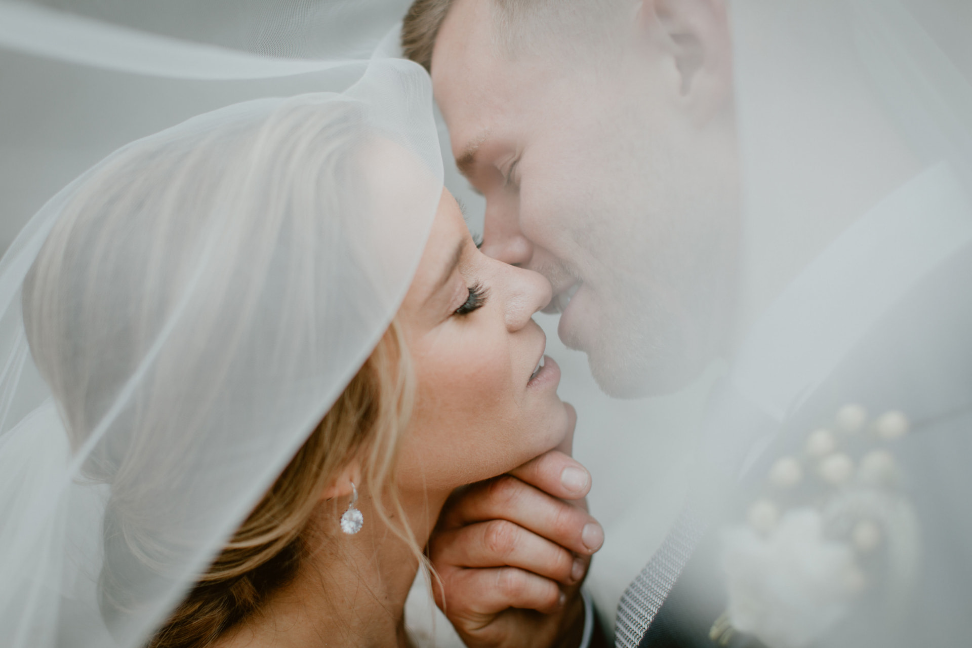 Bride and groom sharing an intimate kiss beneath a sheer veil