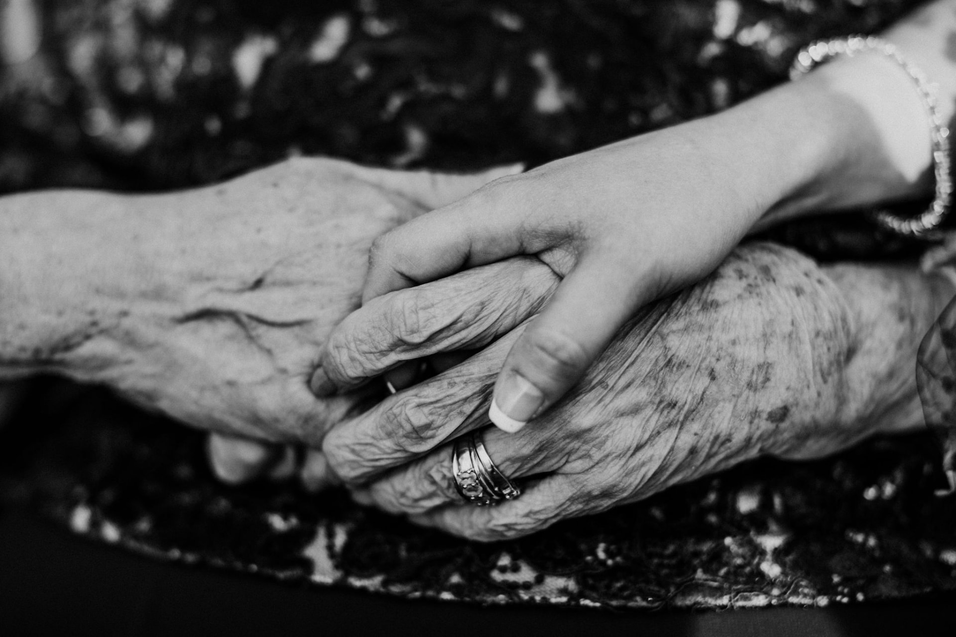 Black and white photo of a bride's hand resting on her grandmother's hands
