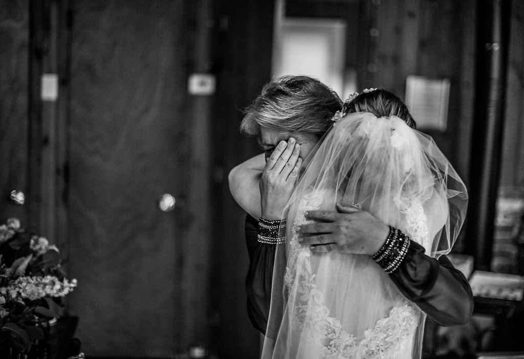 Black and white photo of a mother crying as she embraces her daughter in her veil