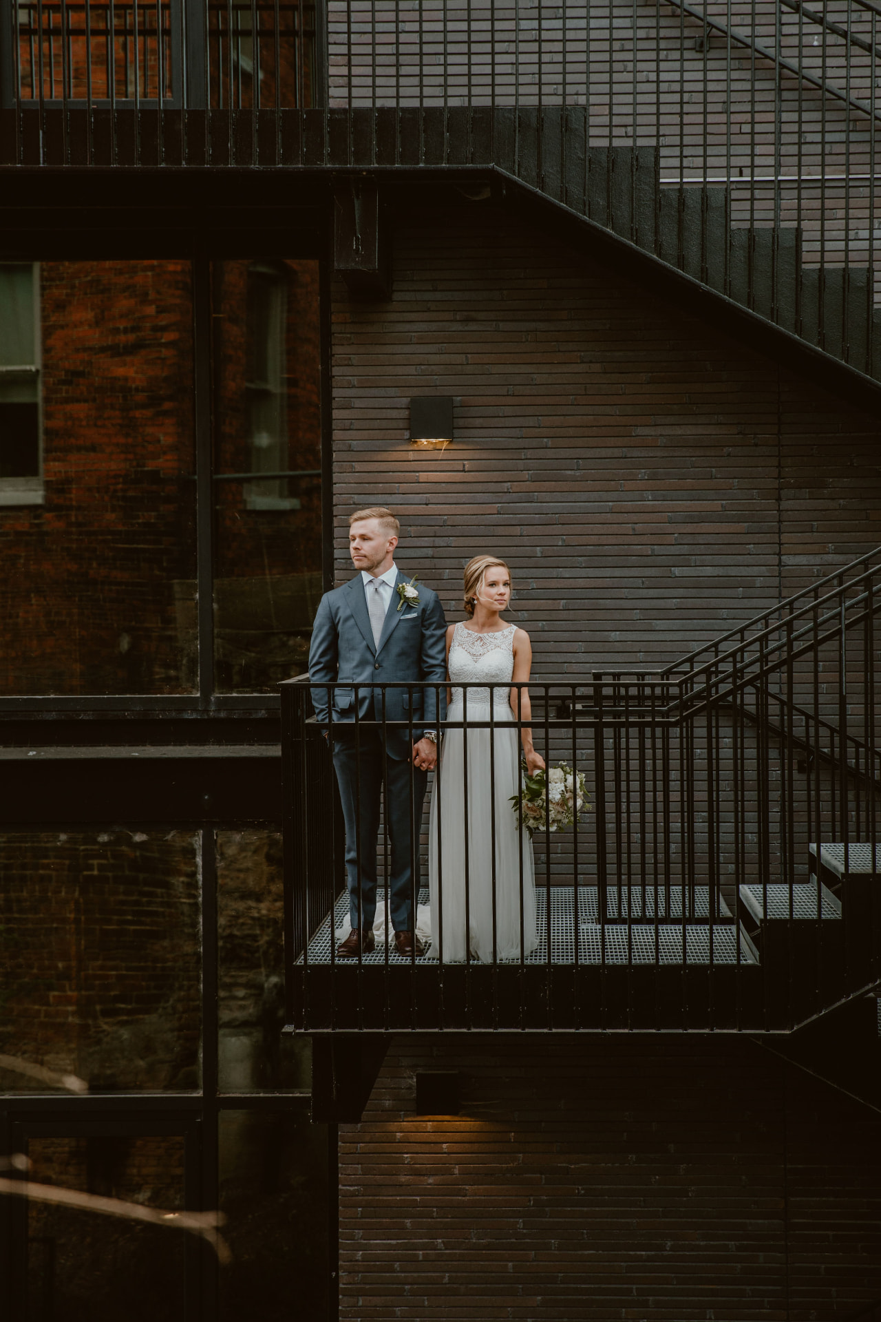 Bride and groom standing on a black fire escape balcony