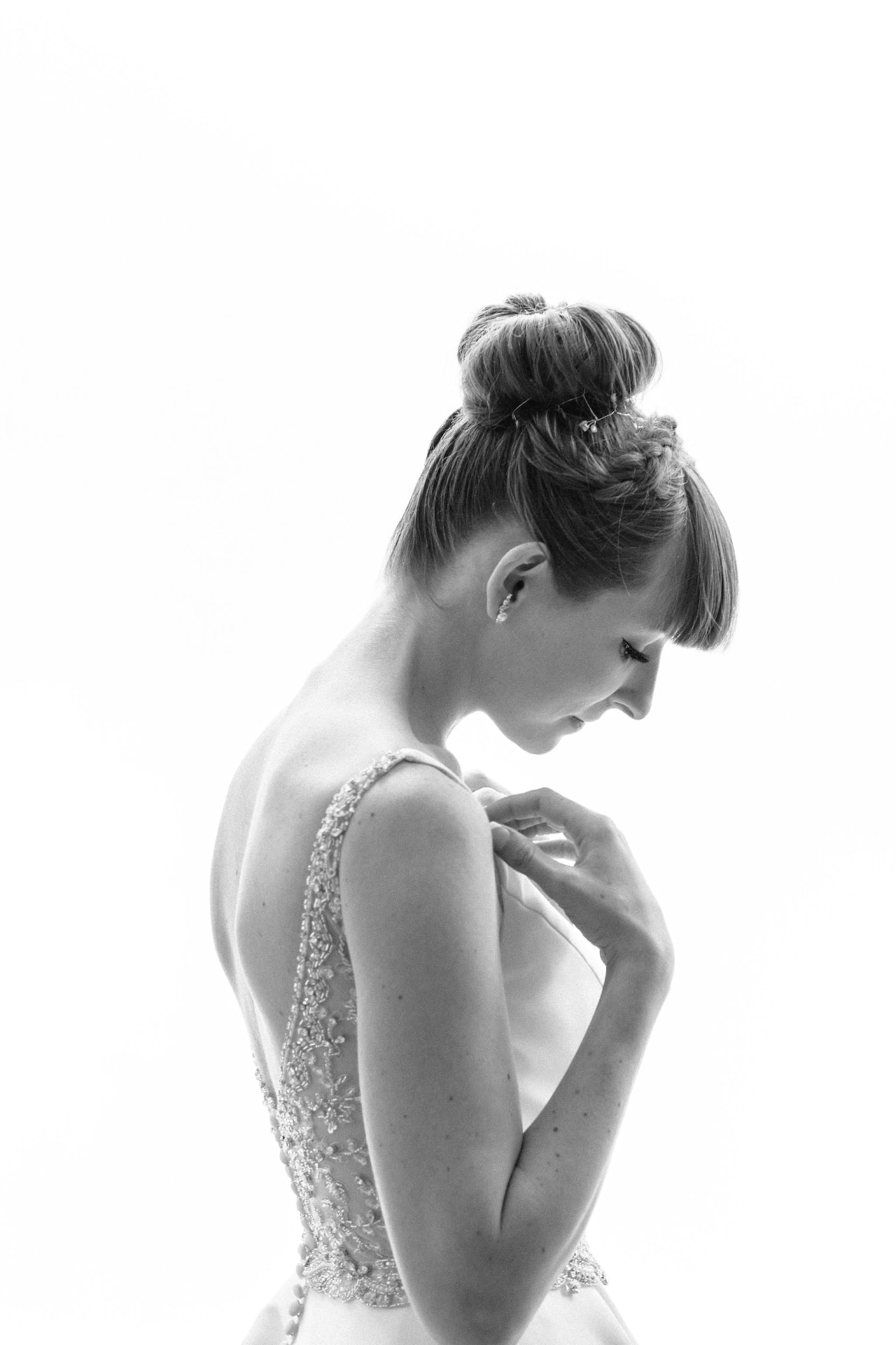 Black and white portrait of a bride adjusting her beaded gown